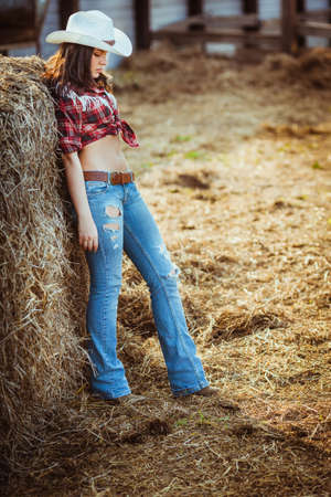 beautiful cowgirl style model posing near hayの写真素材