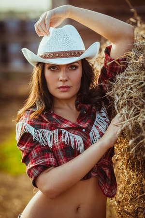 beautiful cowgirl style model posing on farmlandの写真素材