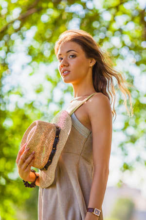 happy girl wearing straw walking in the green summer parkの写真素材