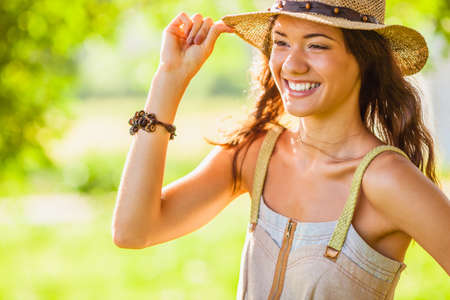 happy girl wearing straw walking in the green summer park, closeup portraitの写真素材