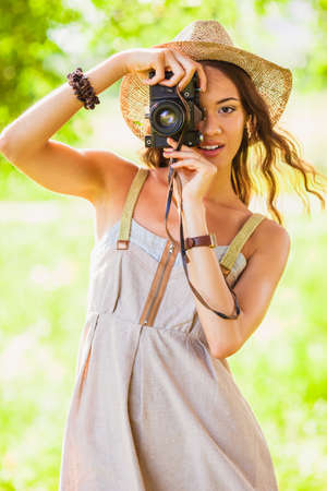 happy young girl shooting with vintage camera in the parkの写真素材