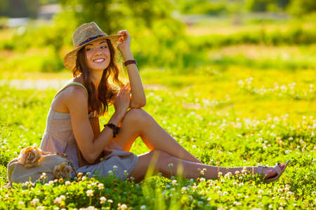 beautiful girl wearing hat with book sitting on grassの写真素材
