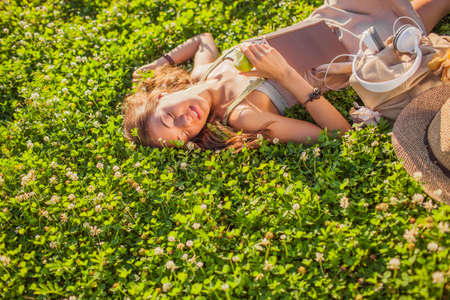 happy beautiful relaxing woman lying on grassの写真素材