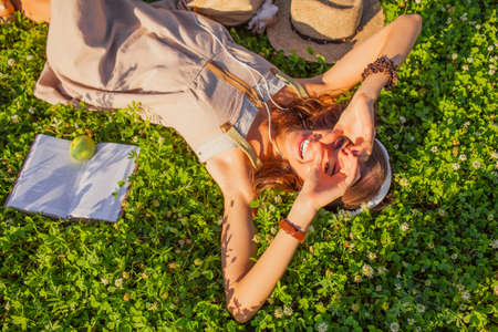 happy woman wearing headphones lying on grass with closed eyesの写真素材