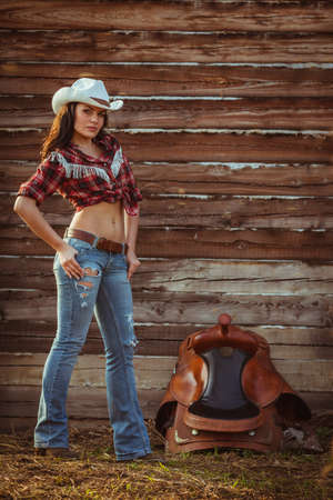 young adult woman wearing country style posing on farmlandの写真素材