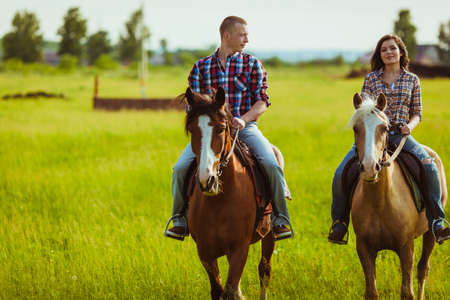 loving couple riding on horses across the fieldの写真素材