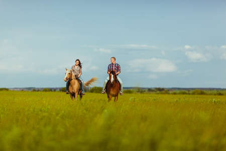 loving couple riding on horses across the fieldの写真素材
