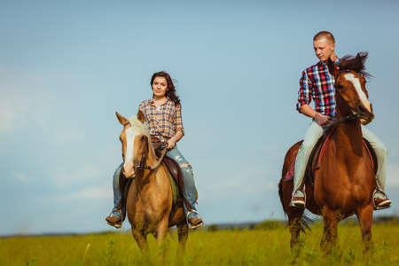 loving couple riding on horses across the fieldの写真素材