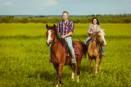 loving couple riding on horses across the fieldの写真素材