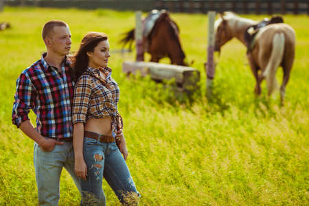 young adult cowboy style couple standing on farm with horsesの写真素材
