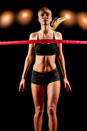 woman finishing through red tape over orange lightsの写真素材