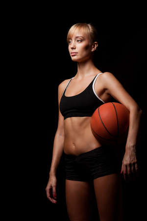 woman standing with basketball over black backgroundの写真素材