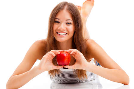 lying woman portrait with big red apple in both handsの写真素材