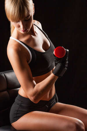 blonde sporty woman holding red dumbbellの写真素材
