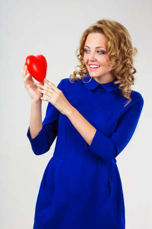 blonde woman  looking at red heart in her handsの写真素材
