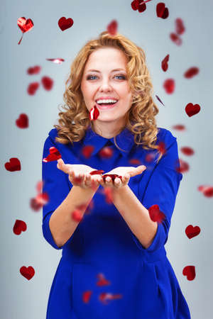 blonde woman catching heart shapes over blue backgroundの写真素材