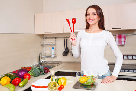 Smiling young housewife mixing fresh saladの写真素材