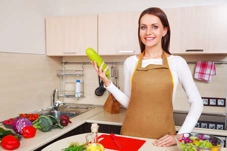 Smiling young housewife mixing fresh saladの写真素材