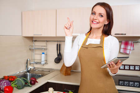 woman using a tablet computer to cook in her kitchenの写真素材