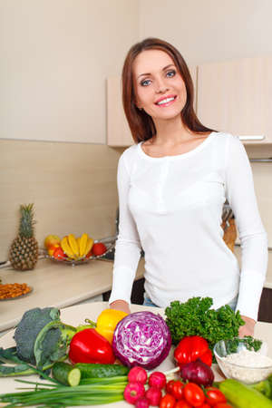 happy smiling young woman with vegetables at kitchenの写真素材