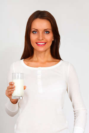 Young brunette woman holding milk against a white backgroundの写真素材