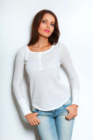 beautiful brunette woman standing near white wallの写真素材