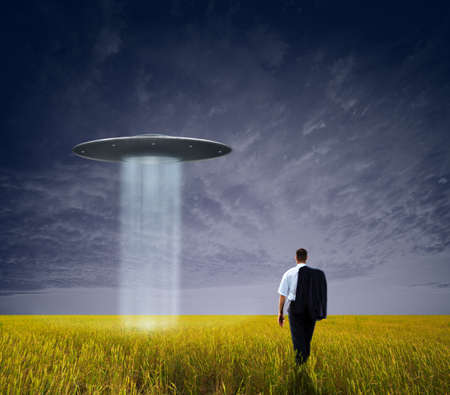 happy businessman standing on field before the sunsetの写真素材