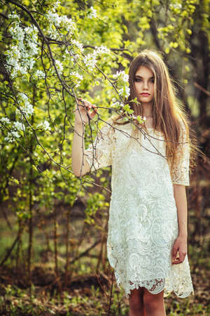 beautiful brunette woman walking outdoors, dramatic theme, spring ground and treesの写真素材