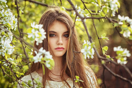 beautiful brunette woman walking outdoors, dramatic theme, spring ground and treesの写真素材