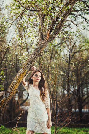 beautiful brunette woman walking outdoors, dramatic theme, spring ground and treesの写真素材
