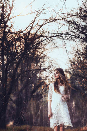 beautiful brunette woman walking outdoors, dramatic theme, spring ground and treesの写真素材