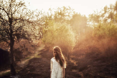 beautiful brunette woman walking outdoors, dramatic theme, spring ground and treesの写真素材