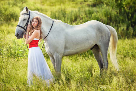 Beautiful sensual women with white horse wearing white dressの写真素材
