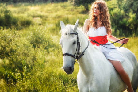 Beautiful women wearing white dress riding on white horse の写真素材