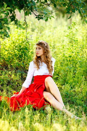 portrait of the woman in red skirt sitting under the treeの写真素材