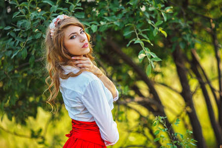 Romantic portrait of the woman in red skirt standing under the treeの写真素材