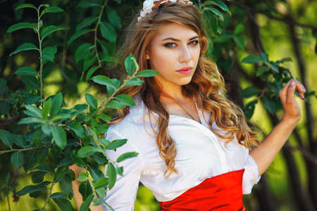 Romantic portrait of the woman in red skirt standing under the treeの写真素材