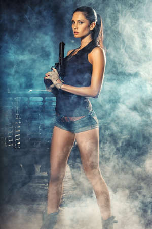 sexy brutal woman standing on factory ruins and holding handgunの写真素材
