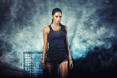sexy brutal woman standing on factory ruins and holding handgunの写真素材