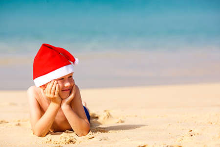 Portrait of cute little boy in Santa hat on beachの写真素材