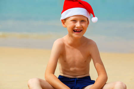Portrait of cute little boy in Santa hat on tropical vacationの写真素材