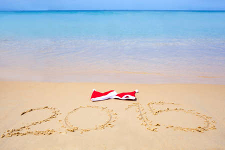 two red santa hats on beach and 2015 text