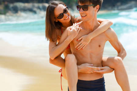 young adult happy couple in sunglasses on the beachの写真素材