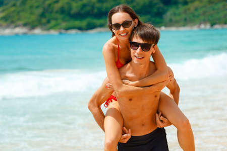 young adult happy couple in sunglasses on the beachの写真素材