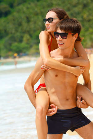 young adult happy couple in sunglasses on the beachの写真素材