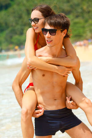 young adult happy couple in sunglasses on the beachの写真素材