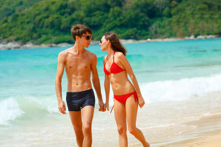 young adult happy couple in sunglasses on the beachの写真素材