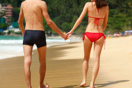 young adult happy couple in sunglasses on the beach, back viewの写真素材