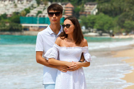 Lovely happy couple wearing sunglasses walking on a tropical beachの写真素材