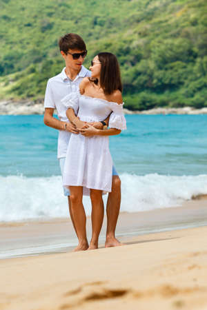 Lovely happy couple wearing sunglasses walking on a tropical beachの写真素材